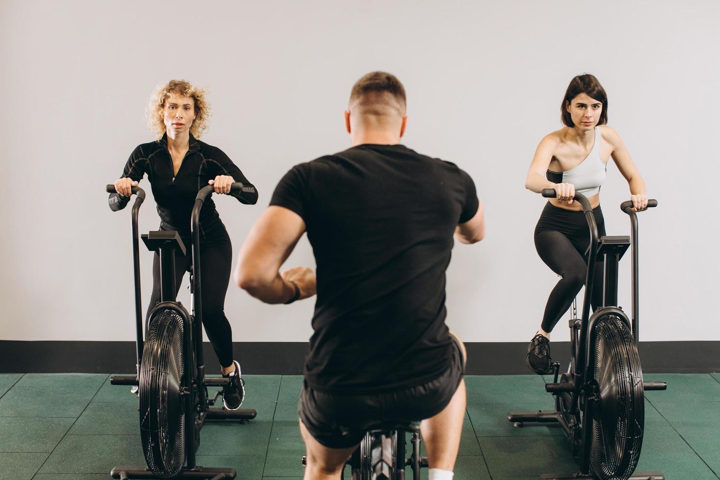 Young man and women using air bike for cardio workout at cross training gym photo