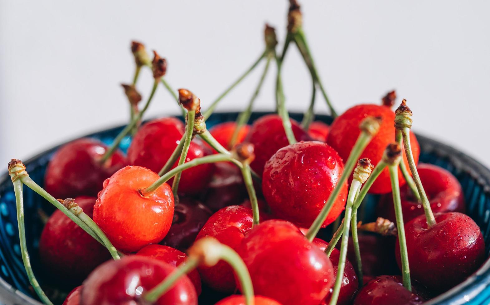 cereza roja jugosa y brillante en las gotas de agua en el plato foto