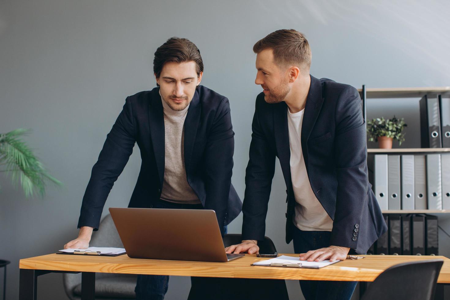Business teamwork - two corporate businessmen working together on laptop photo