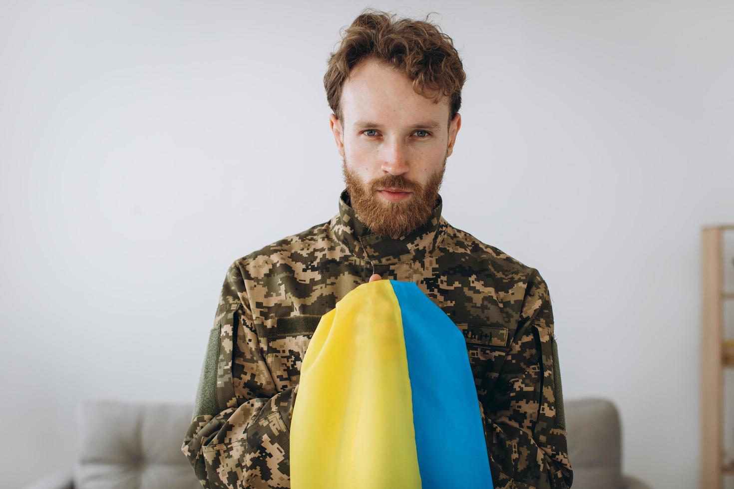 Ukrainian patriot soldier in military uniform holding a yellow and blue flag on a white background photo