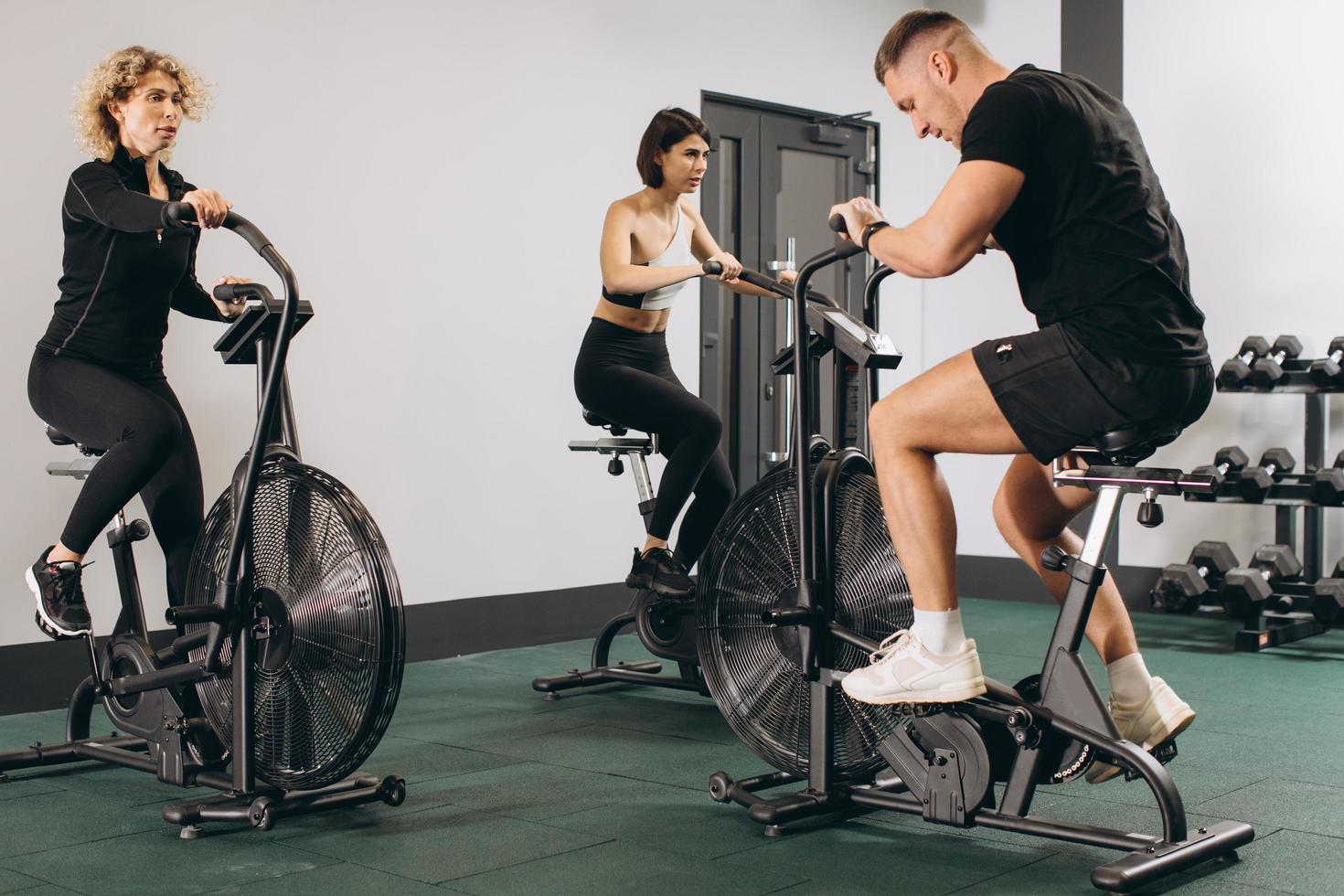 Young man and women using air bike for cardio workout at cross training gym photo