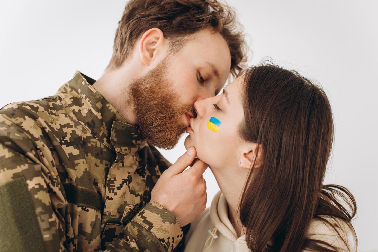 Ukrainian couple, military bearded man in uniform kisses his girlfriend at home photo