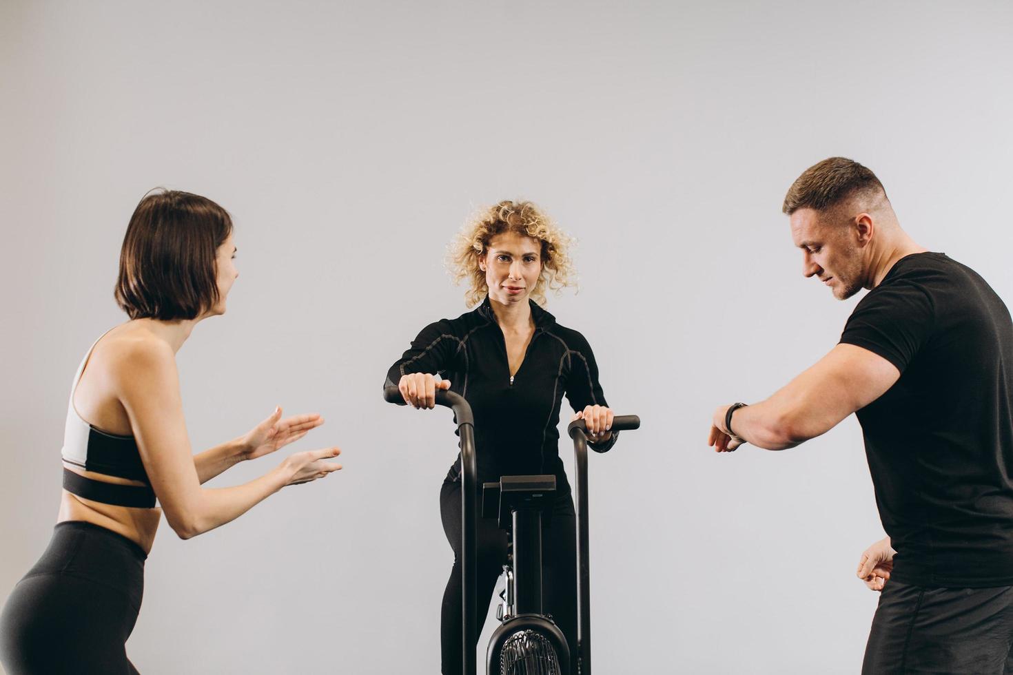 Woman exercising on air bike at gym with friends motivating. photo