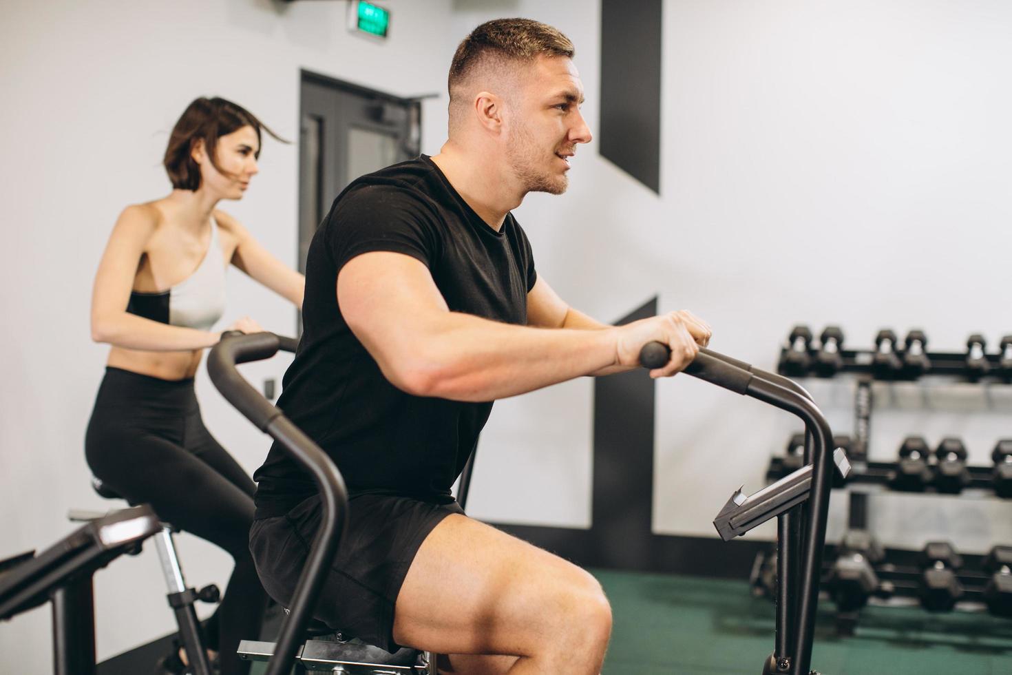 Young man and woman using air bike for cardio workout at cross training gym photo