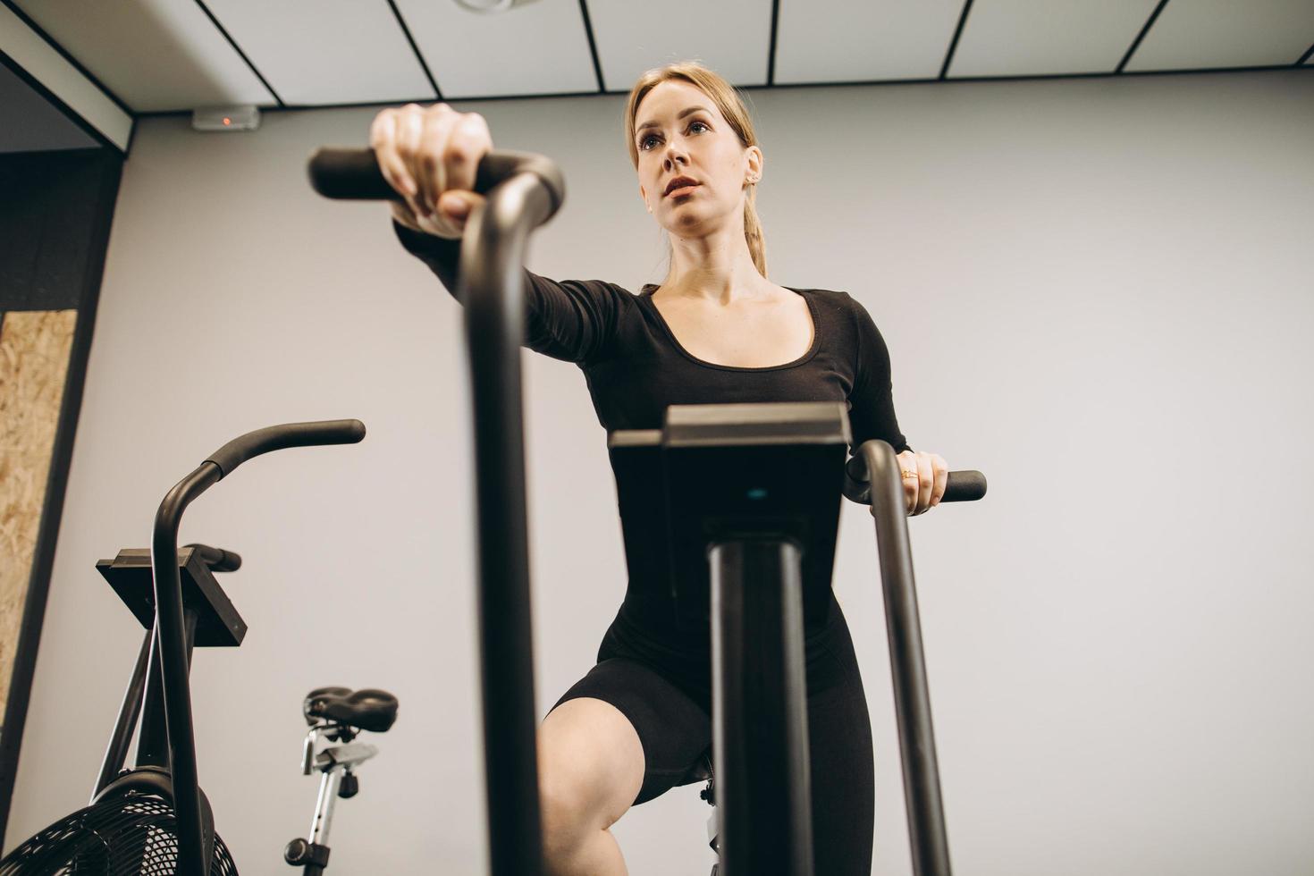 Crossfit woman doing intense cardio training on exercise air bike photo