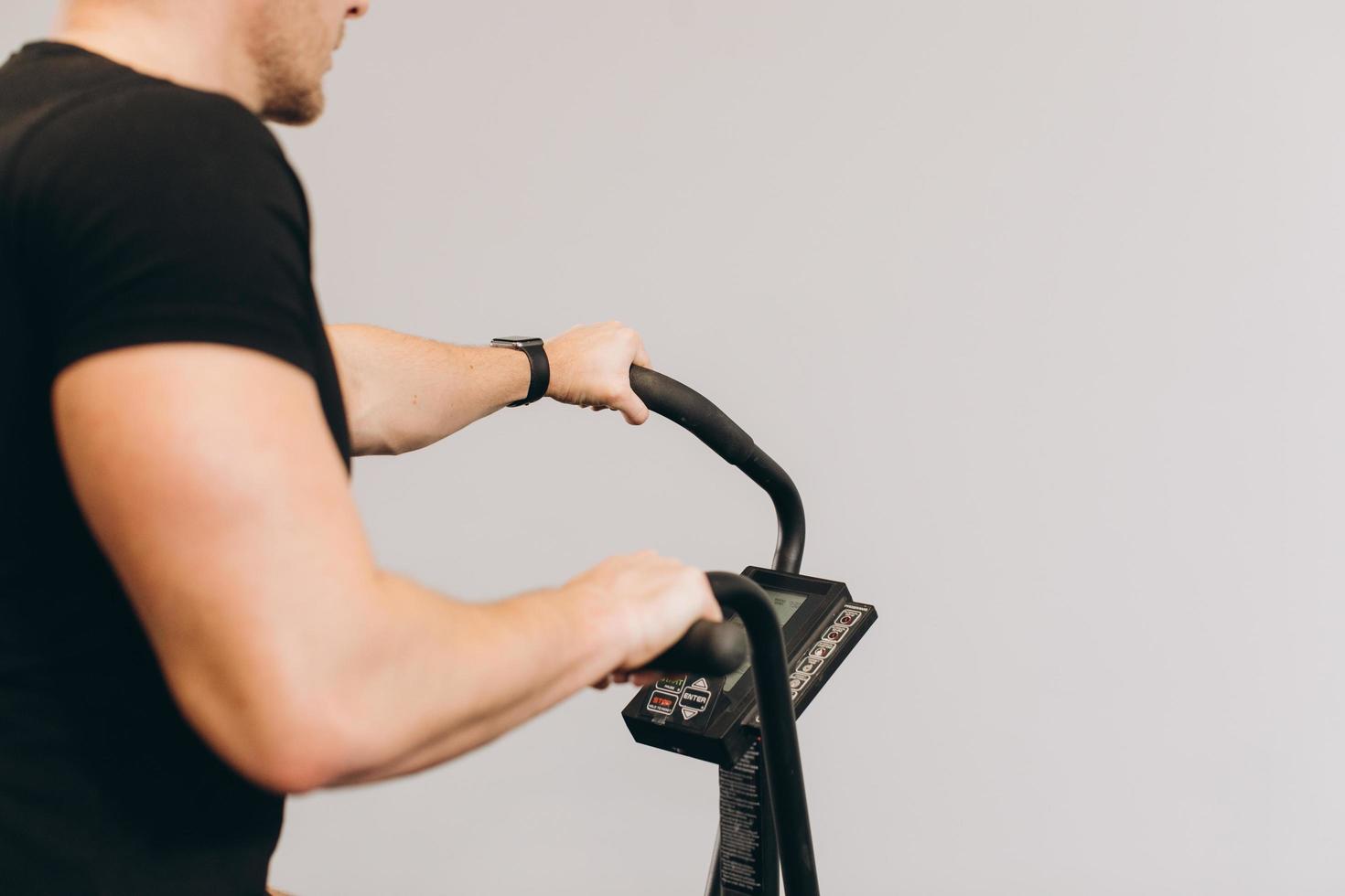 Male using air bike for cardio workout at cross training gym. photo