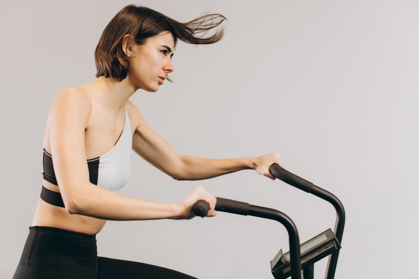 mujer crossfit haciendo entrenamiento cardiovascular intenso en bicicleta de aire foto