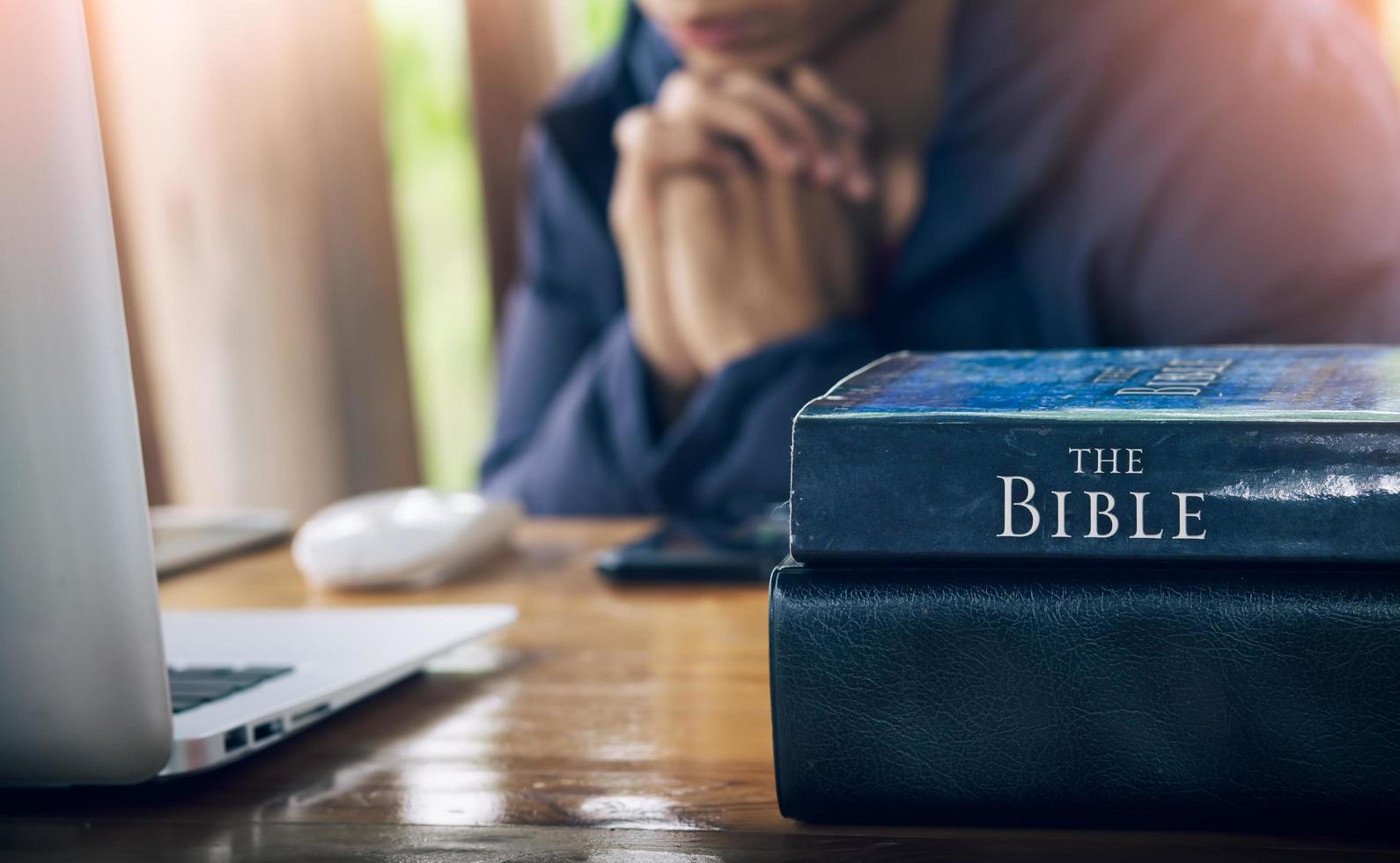 Close up the Bible with a christian man praying in background, pray and worship concept. photo