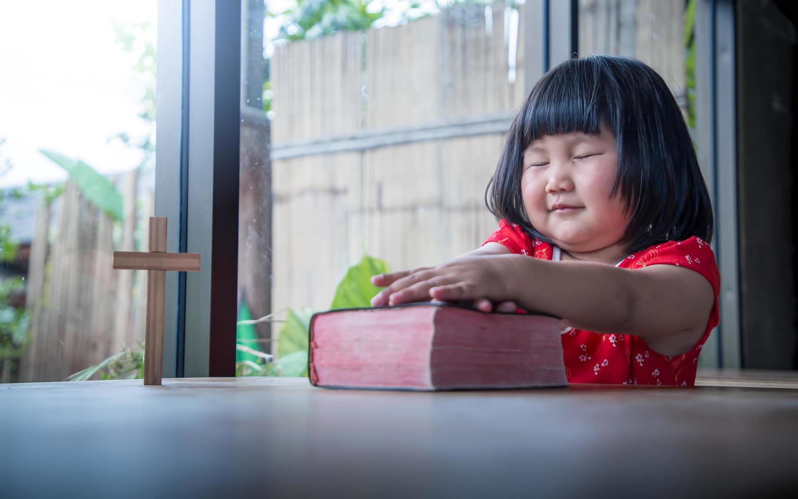 Little girl praying on bible at home, child's pure faith photo