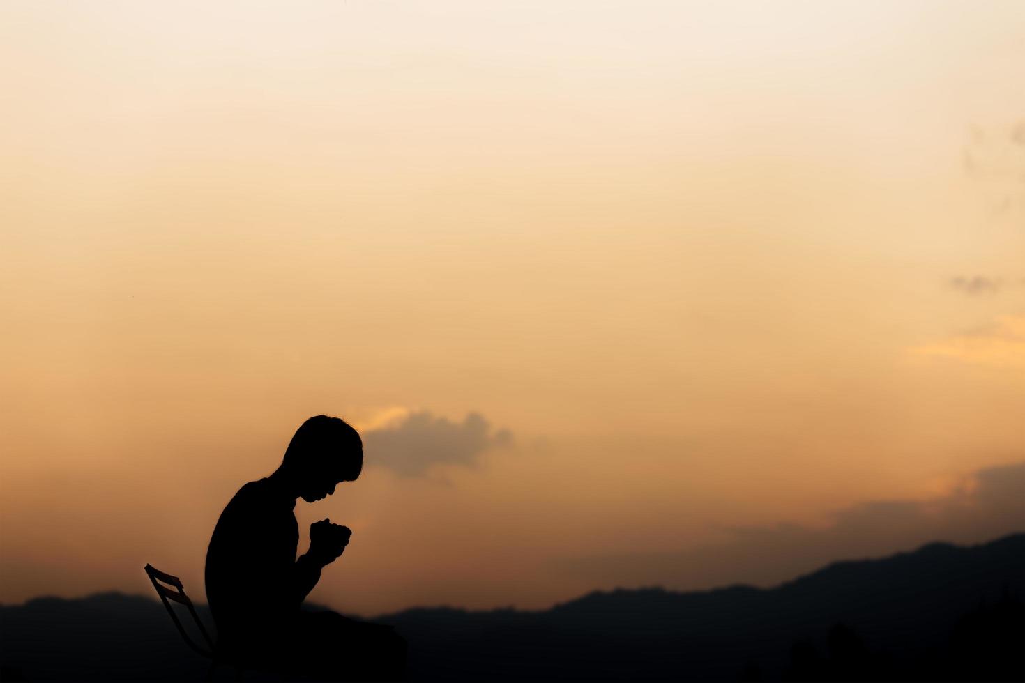 Silhouette of a man holding hands and prayer on mountain at sunset. concept of religion. photo