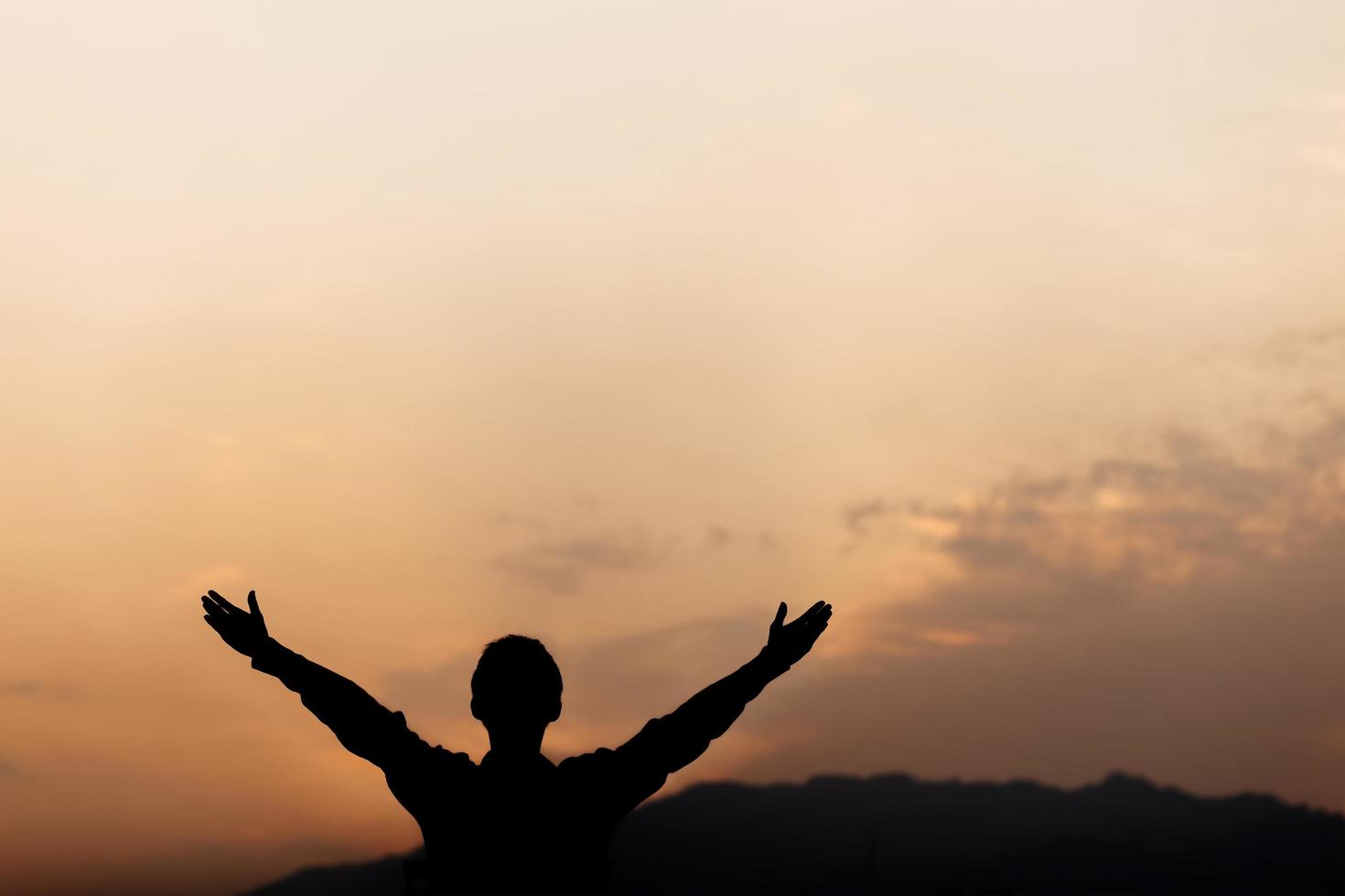 Silhouette of a man lift hands up and prayer at sunset. concept of religion. photo