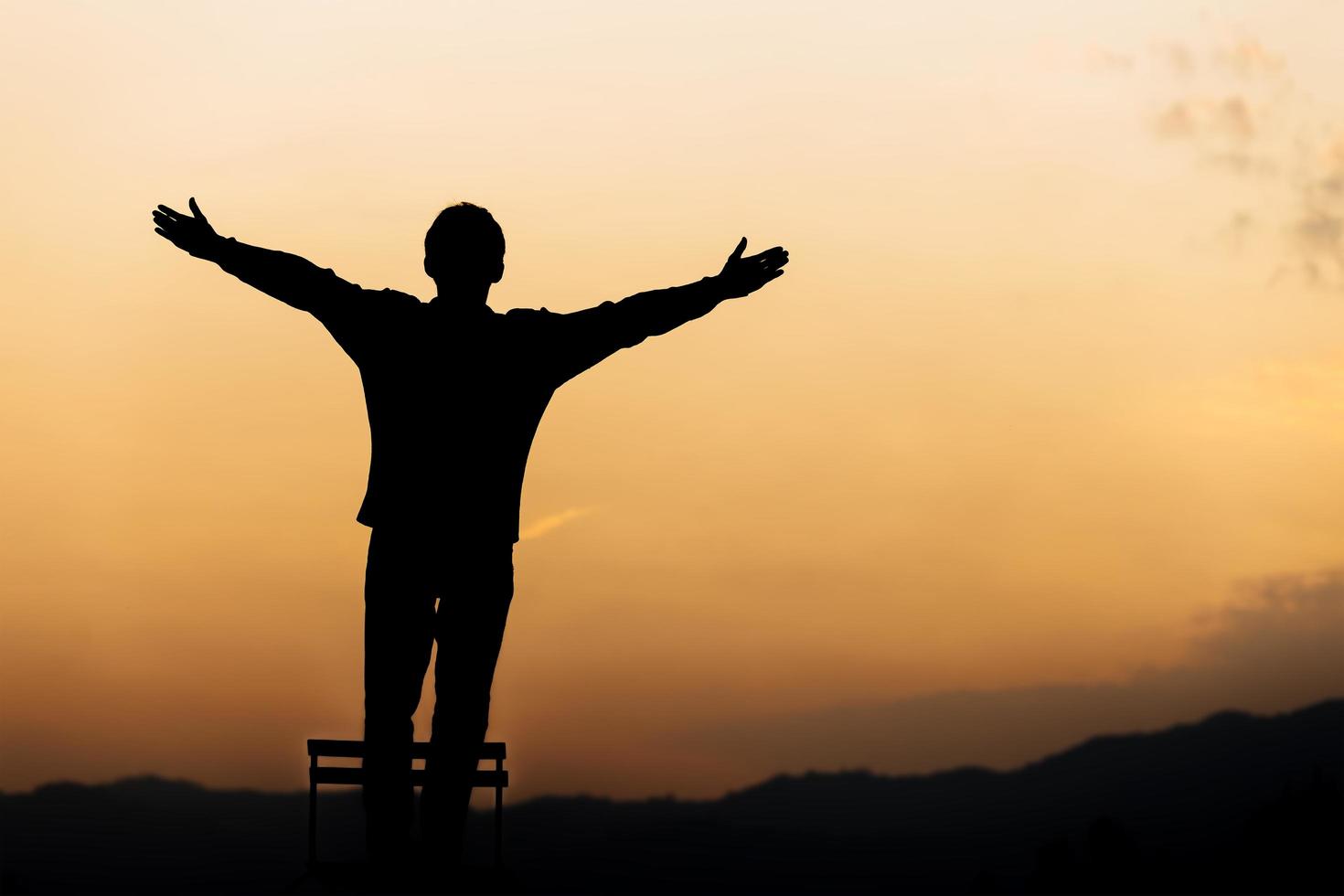 silueta de un hombre de pie levanta las manos y reza y adora a Dios al atardecer. concepto de religión. foto