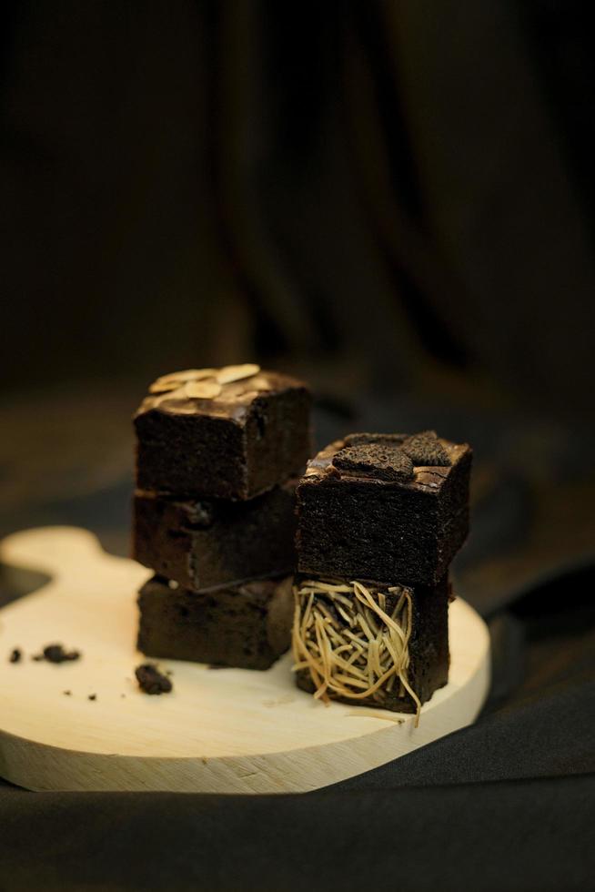 Pieces of fresh brownie on back background. Delicious chocolate pie photo