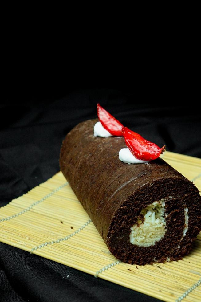 delicious chocolate roll cake with chocolate cream, dark blue background. selective focus photo