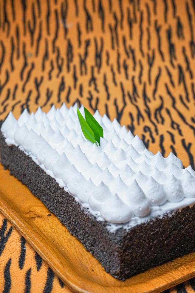 Chocolate Sponge Cake filled with whipped cream on white plate with fork photo