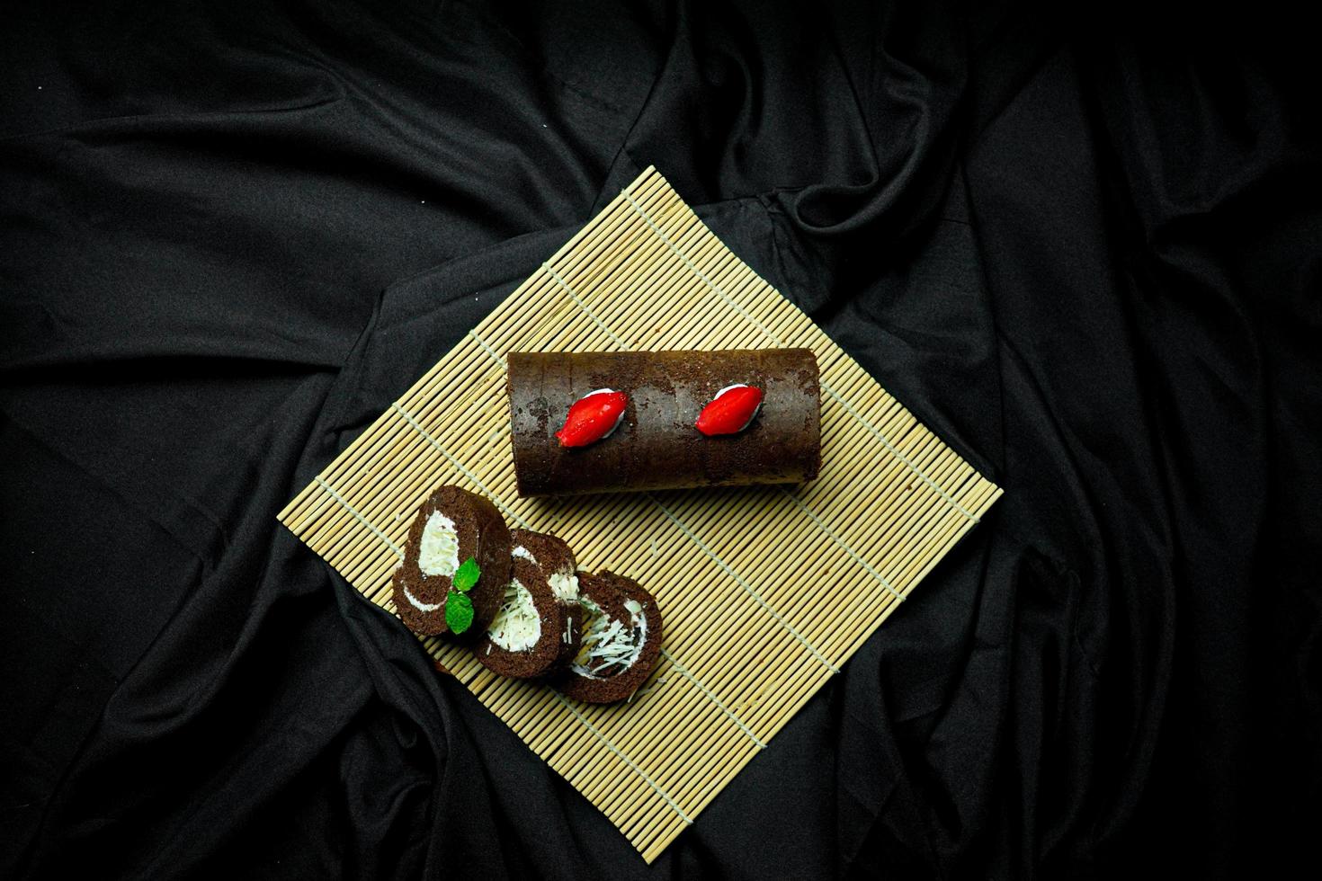 delicious chocolate roll cake with chocolate cream, dark blue background. selective focus photo