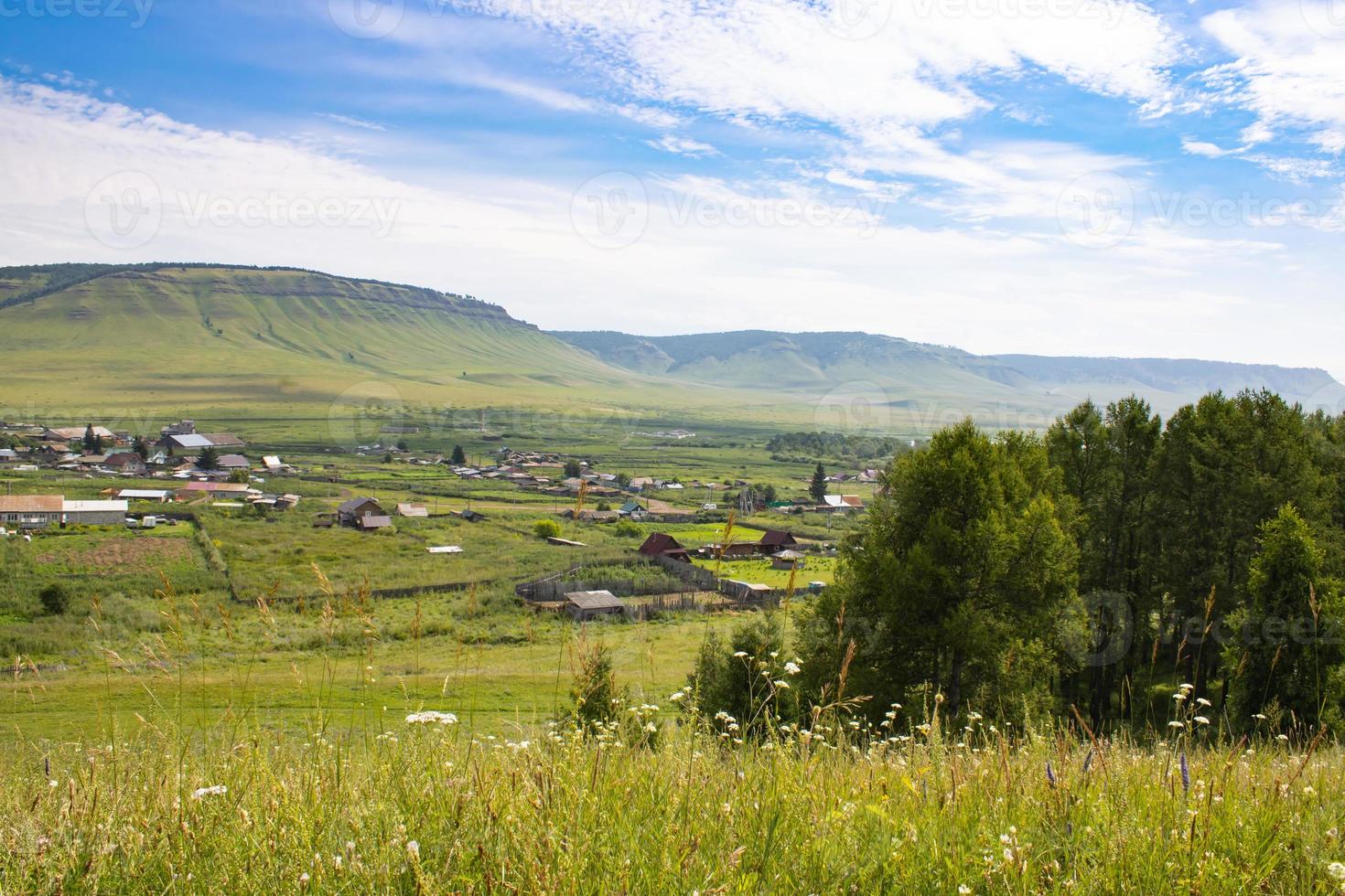 Picturesque landscape of a small village among the mountains in summer. Small houses among green grass and trees. photo