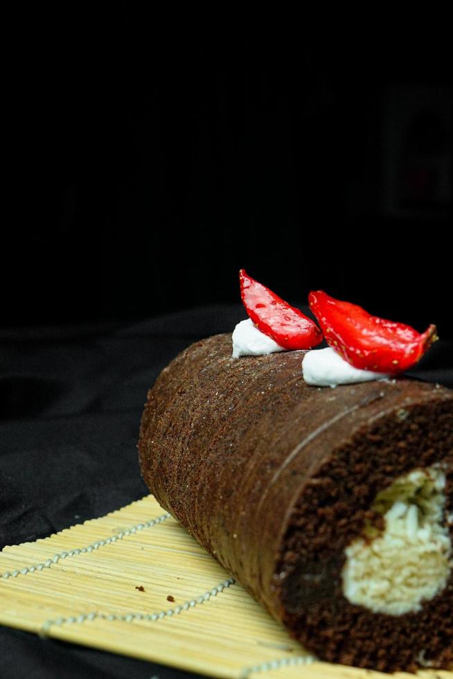 delicious chocolate roll cake with chocolate cream, dark blue background. selective focus photo