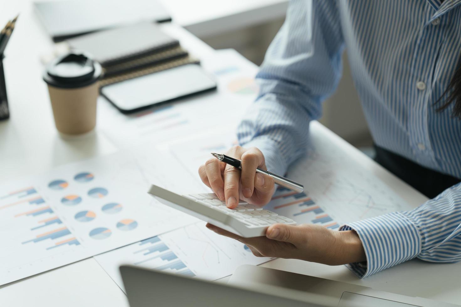 contador que trabaja en el escritorio usando una calculadora para calcular el informe financiero en la oficina. foto