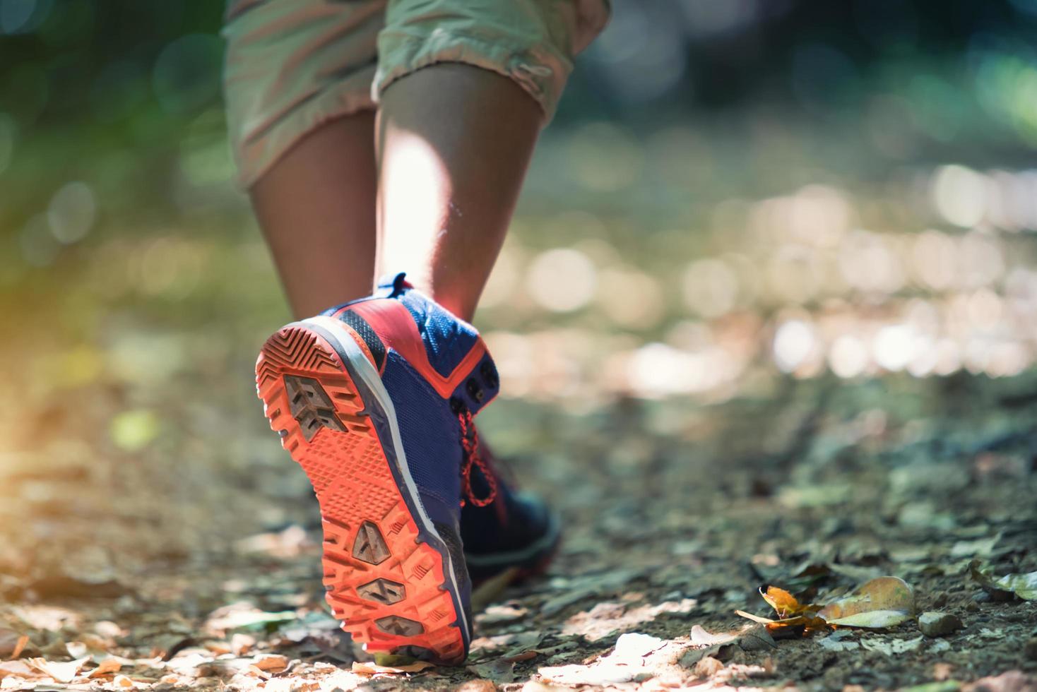 Close-up of female hiker feet and shoe walking on forest trail. Travel Concept photo