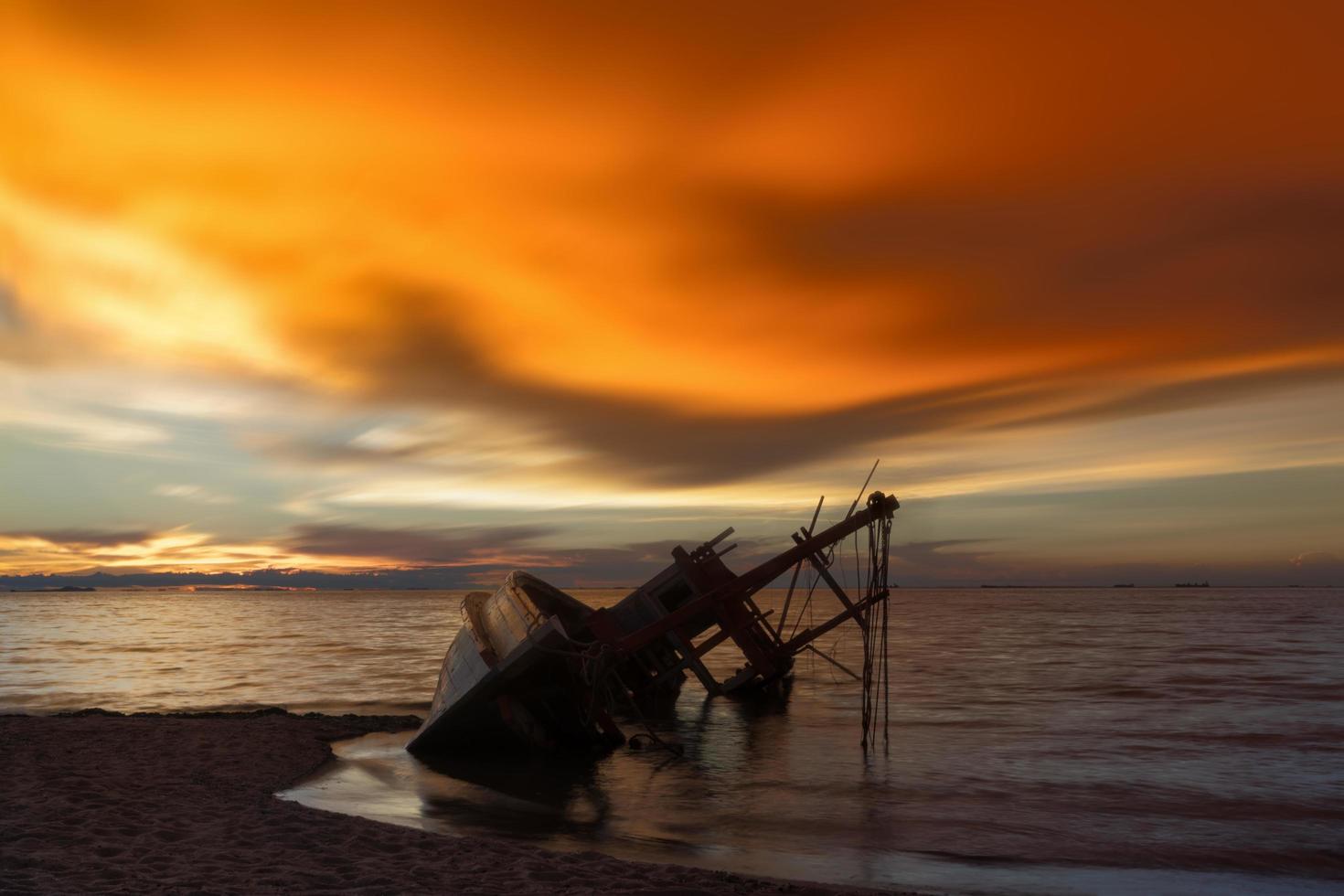 Abandoned shipwreck of wood fishing boat on beach at twilight time photo