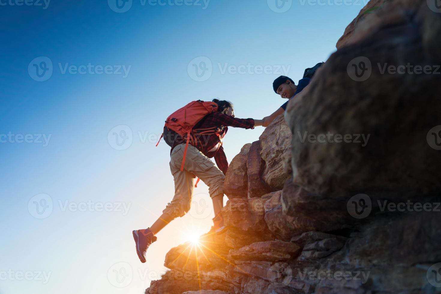 Young asian couple climbing up on the mountain,hiking and team work concept. photo