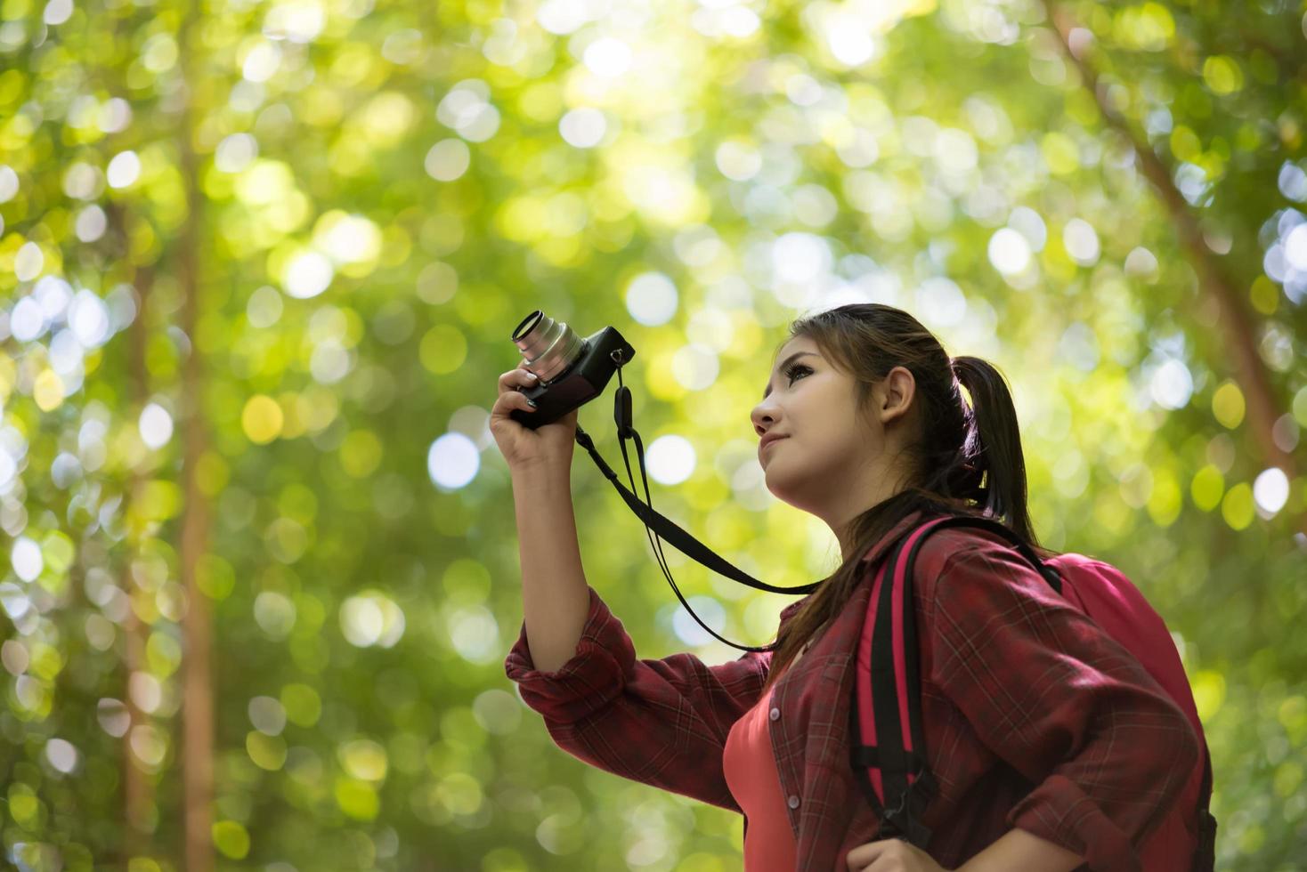 mujer fotógrafa con cámara en el parque sobre fondo verde foto