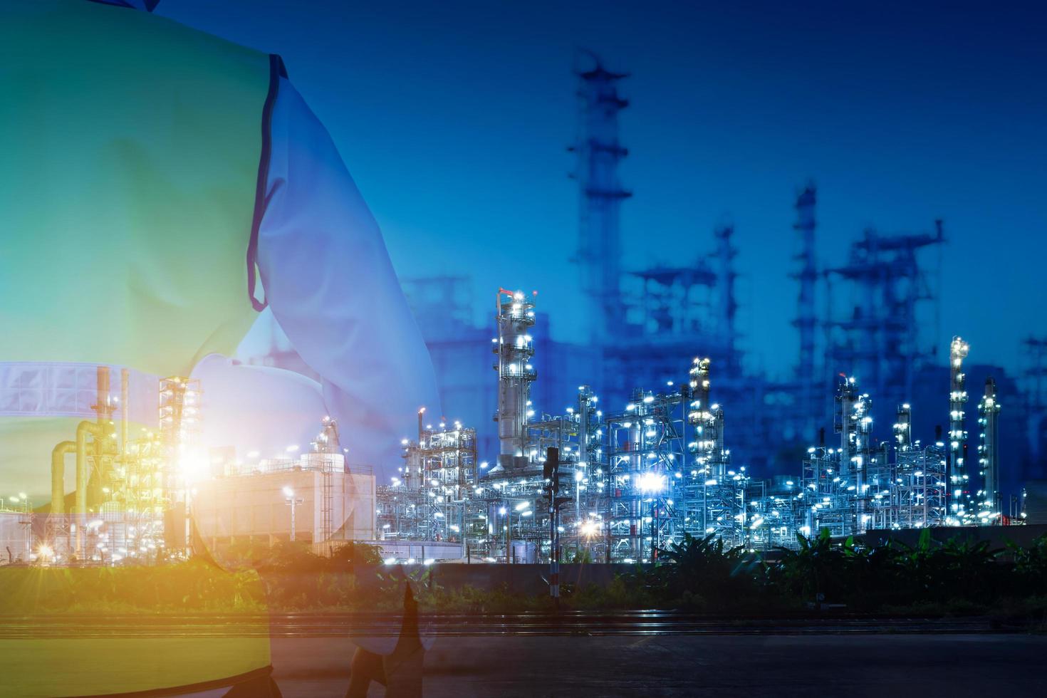 Double exposure of engineer holds a safety hat facing the refinery photo