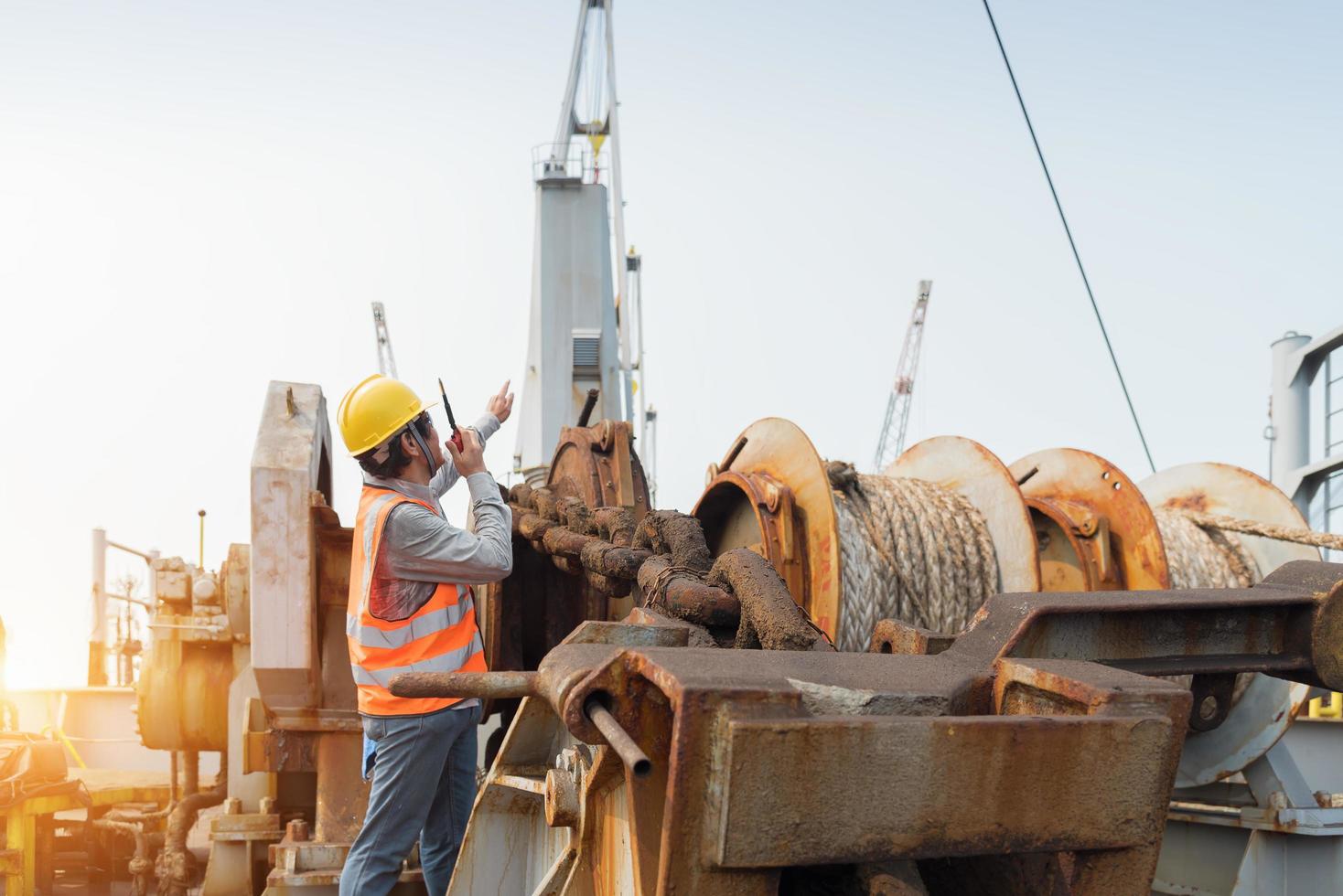 Foreman using walkie-talkie and safety helmet to work in cargo ship photo