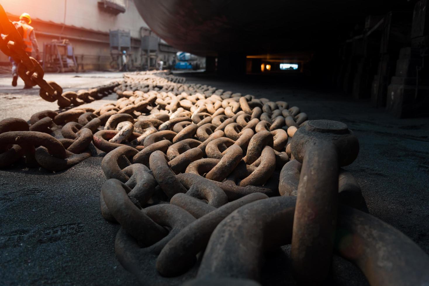 Close up view of big metal anchor chain of cargo ship in dry dock for repairs and painting in shipyard photo