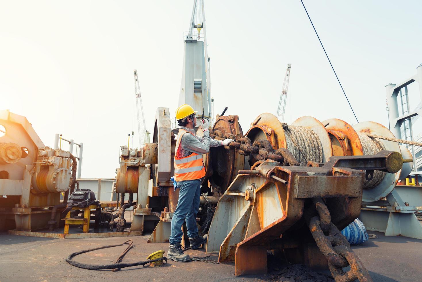 Foreman using walkie-talkie and safety helmet to work in cargo ship photo