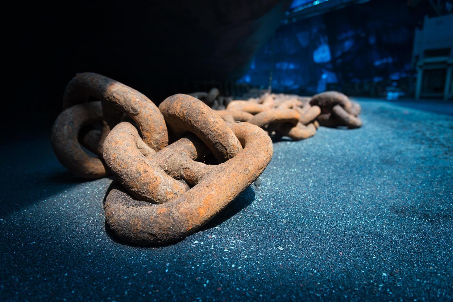 Close up view of big metal anchor chain of cargo ship in dry dock for repairs and painting in shipyard photo