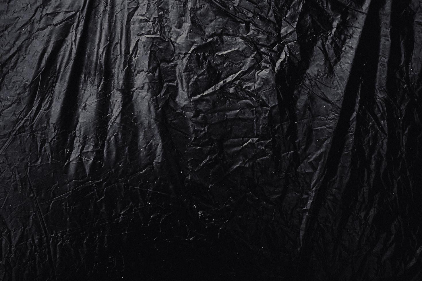 a transparent stretch plastic wrap on black background. realistic plastic wrap texture for overlay and effect. wrinkled plastic pattern for creative and decorative design. photo