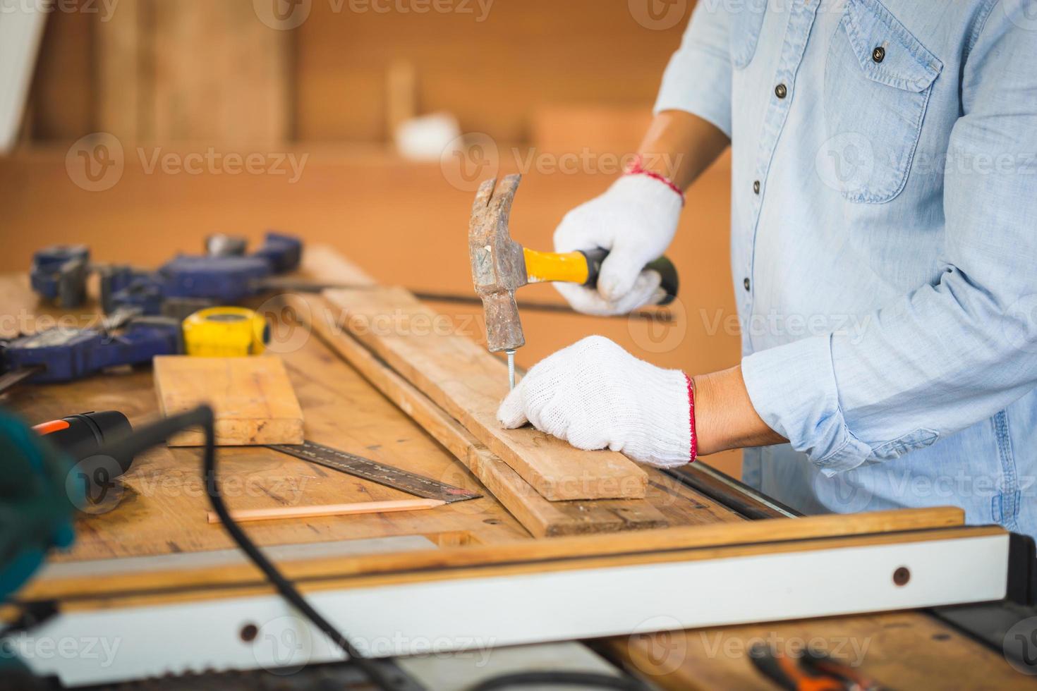 Craftsman using hammer hobnailed in workshop, Carpenter using the hammer hit a nail for assembly wood in a carpentry workshop photo