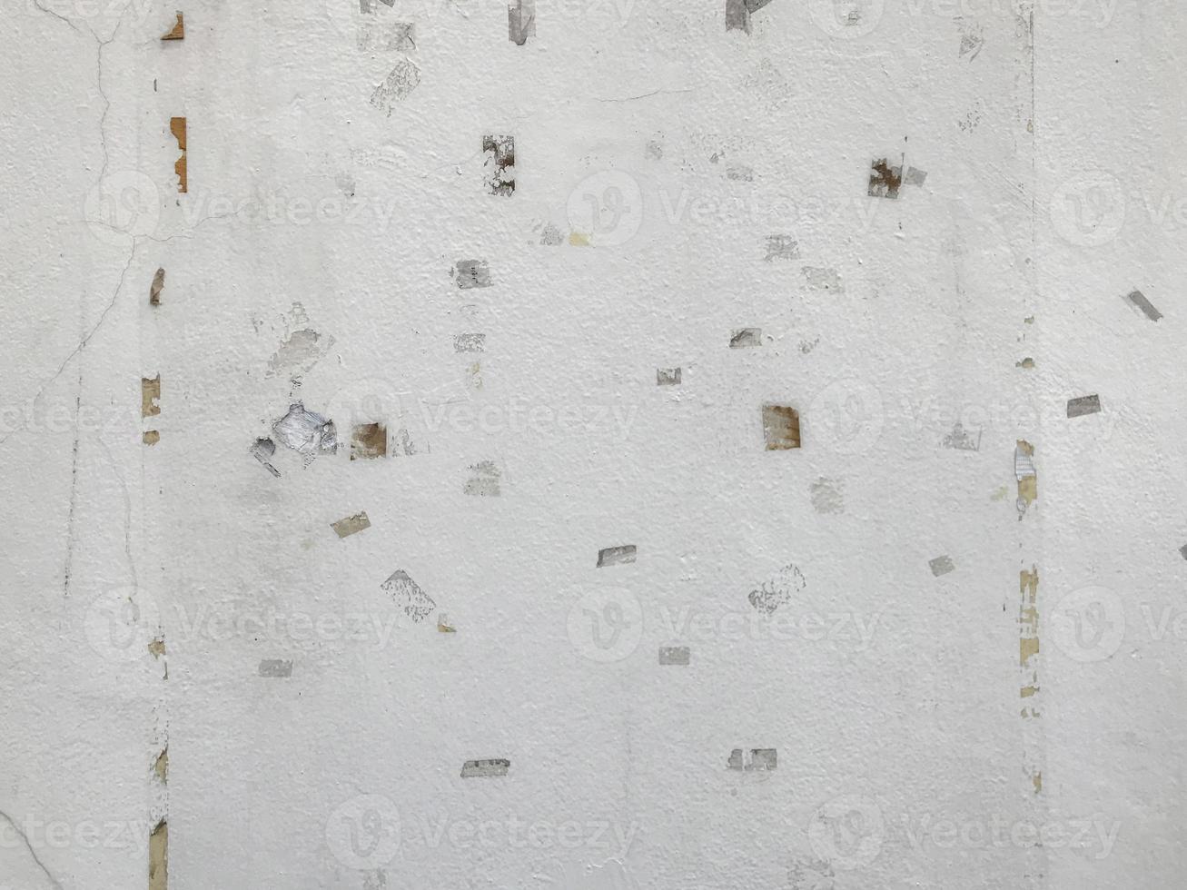 Old white cement wall with traces of masking tape from pasting the poster. photo