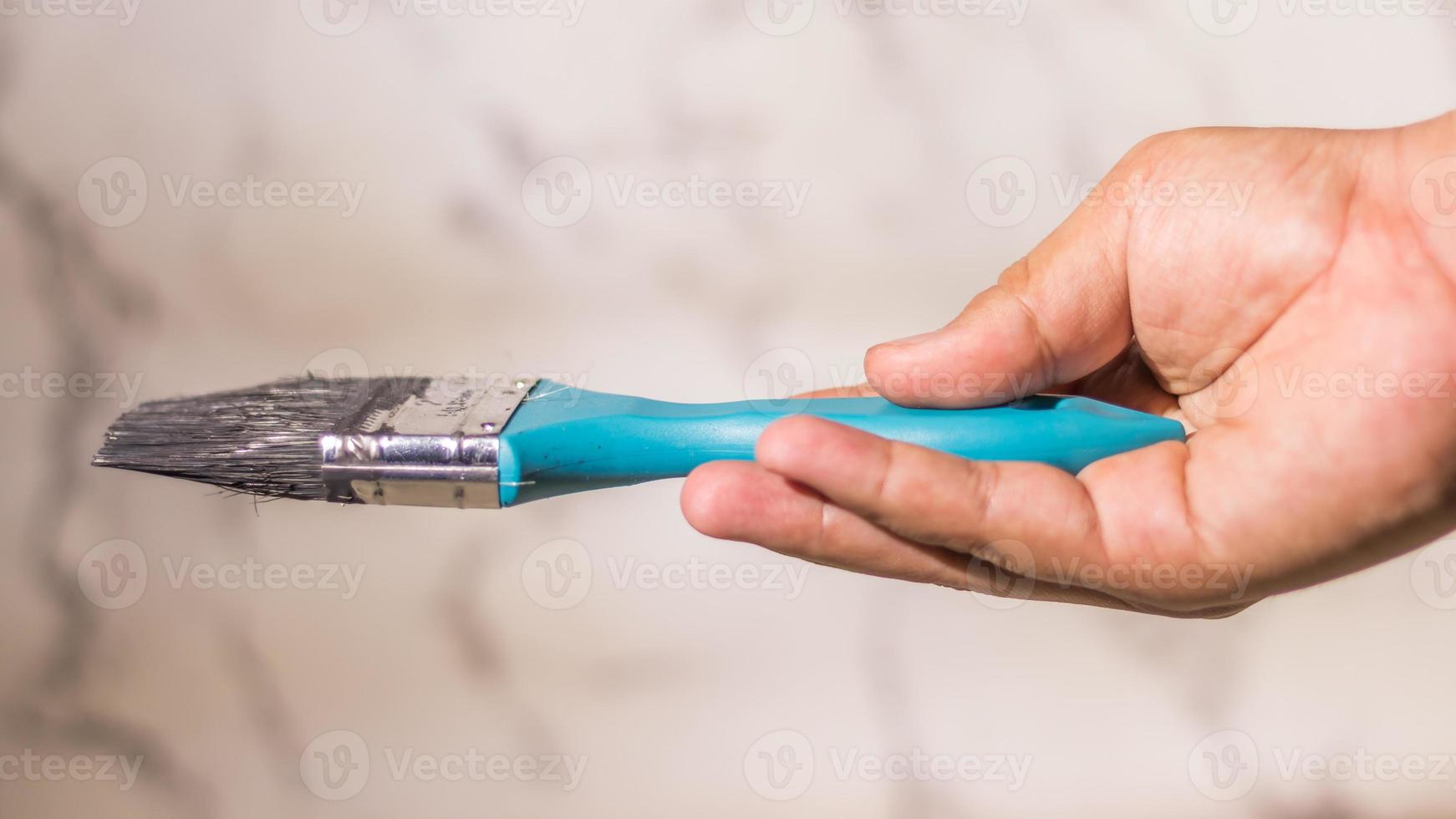 Close up male hand holding a medium size  paint brush on abstract white background photo