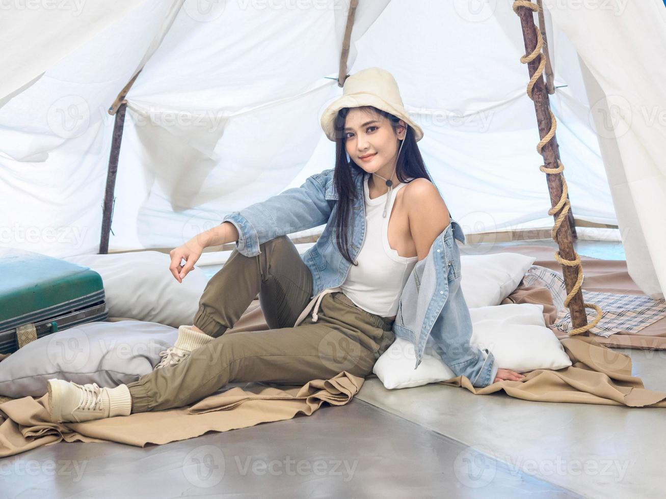 Portrait beautiful young girl woman Asian pretty smile one person alone sitting on chair camping with teble flower in vase lantern red travel trip in front tent freedom relax happy enjoy in vacation photo