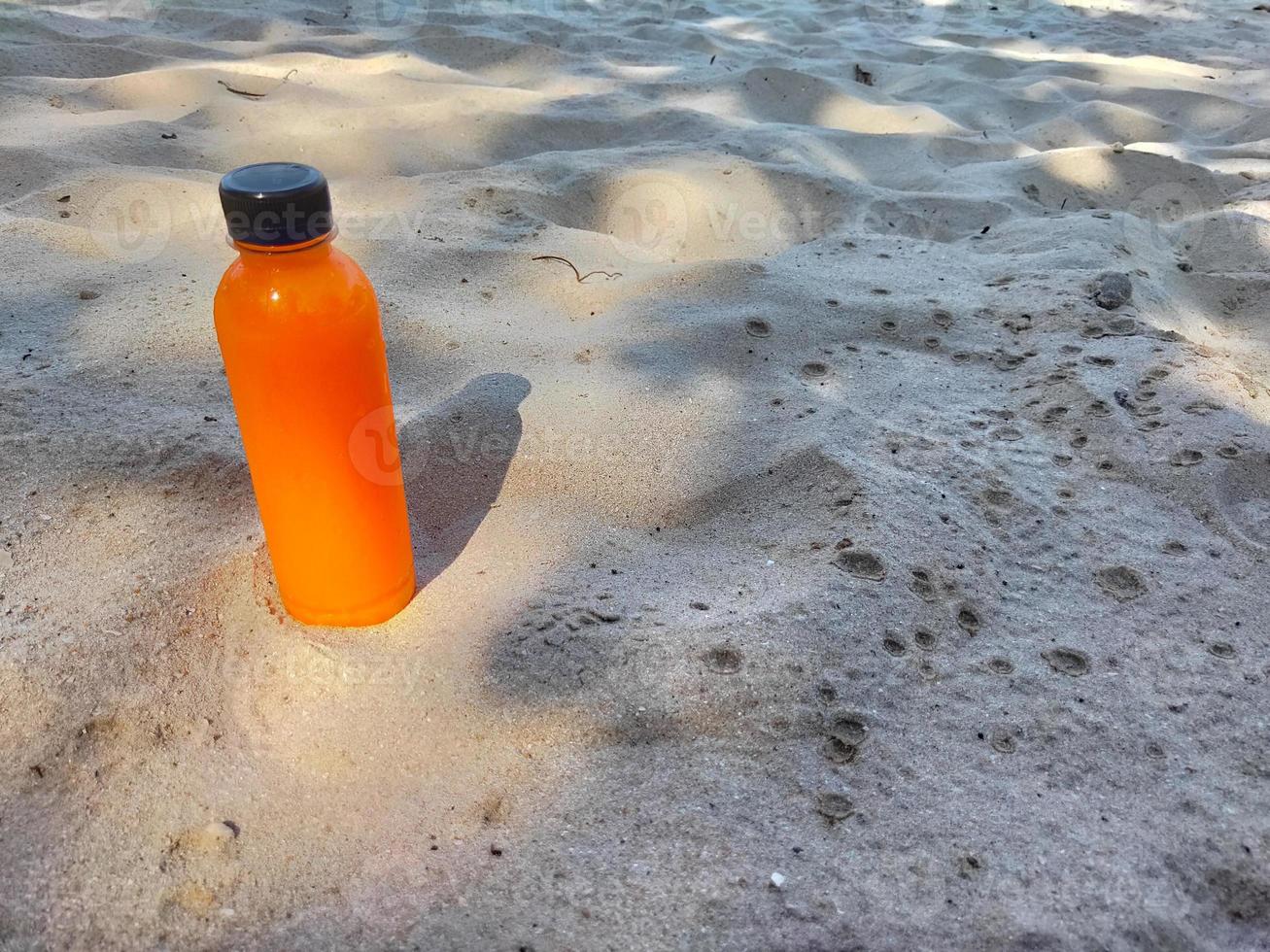 A bottle of orange juice on the beach photo