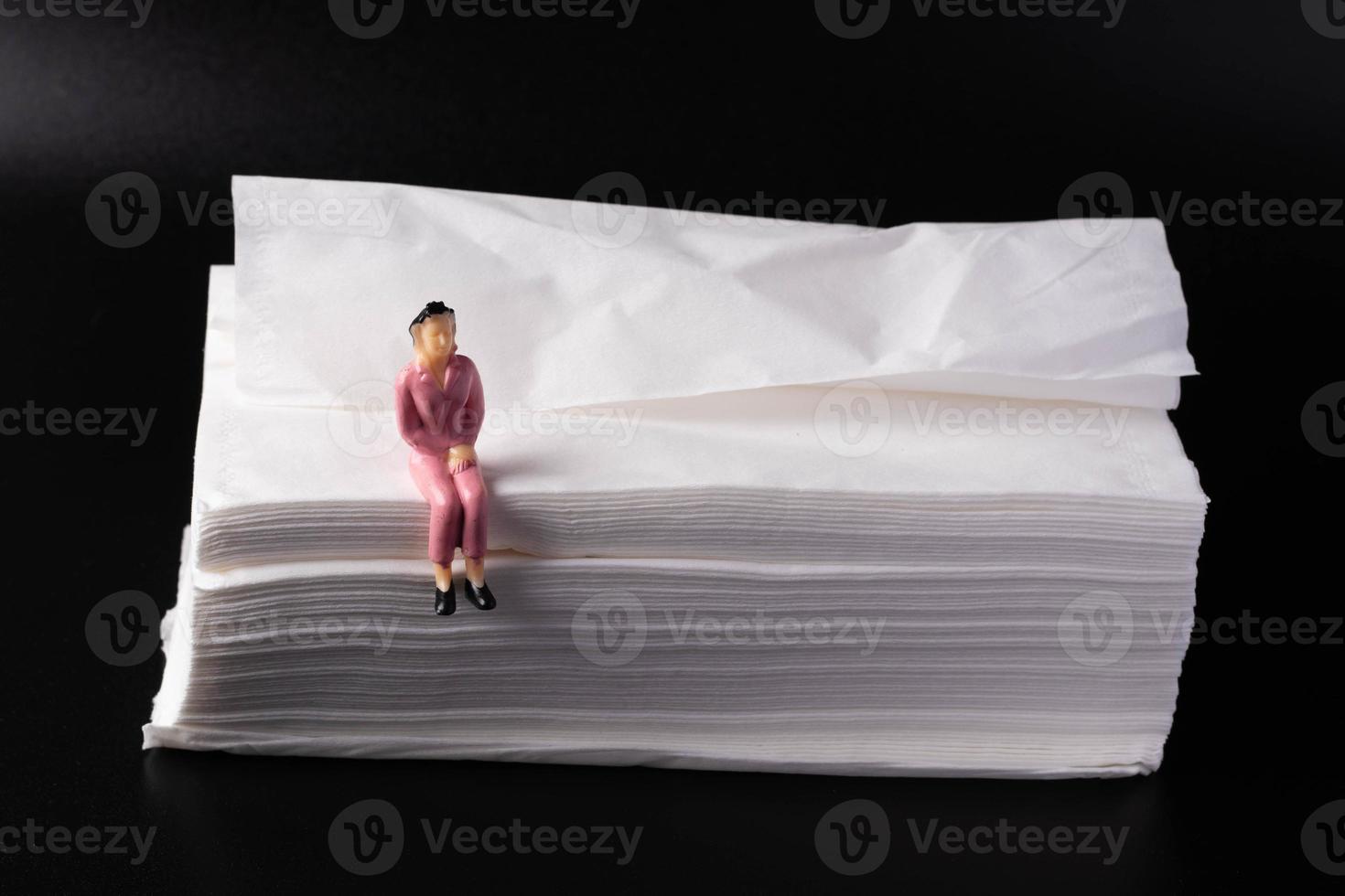 Miniature people, sitting on a pile of white paper photo