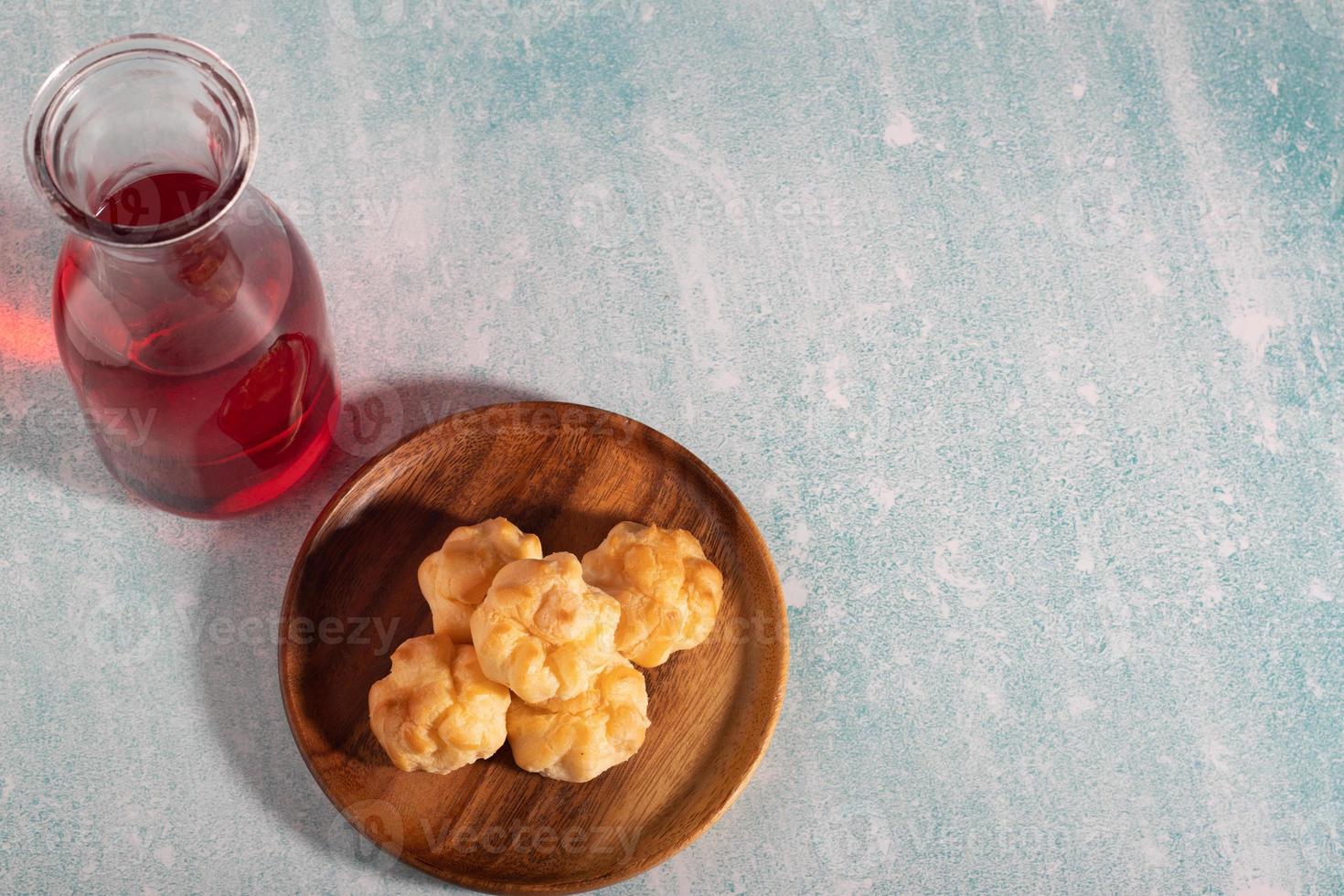 Eclair in a wooden dish with a glass bottle of red water. photo