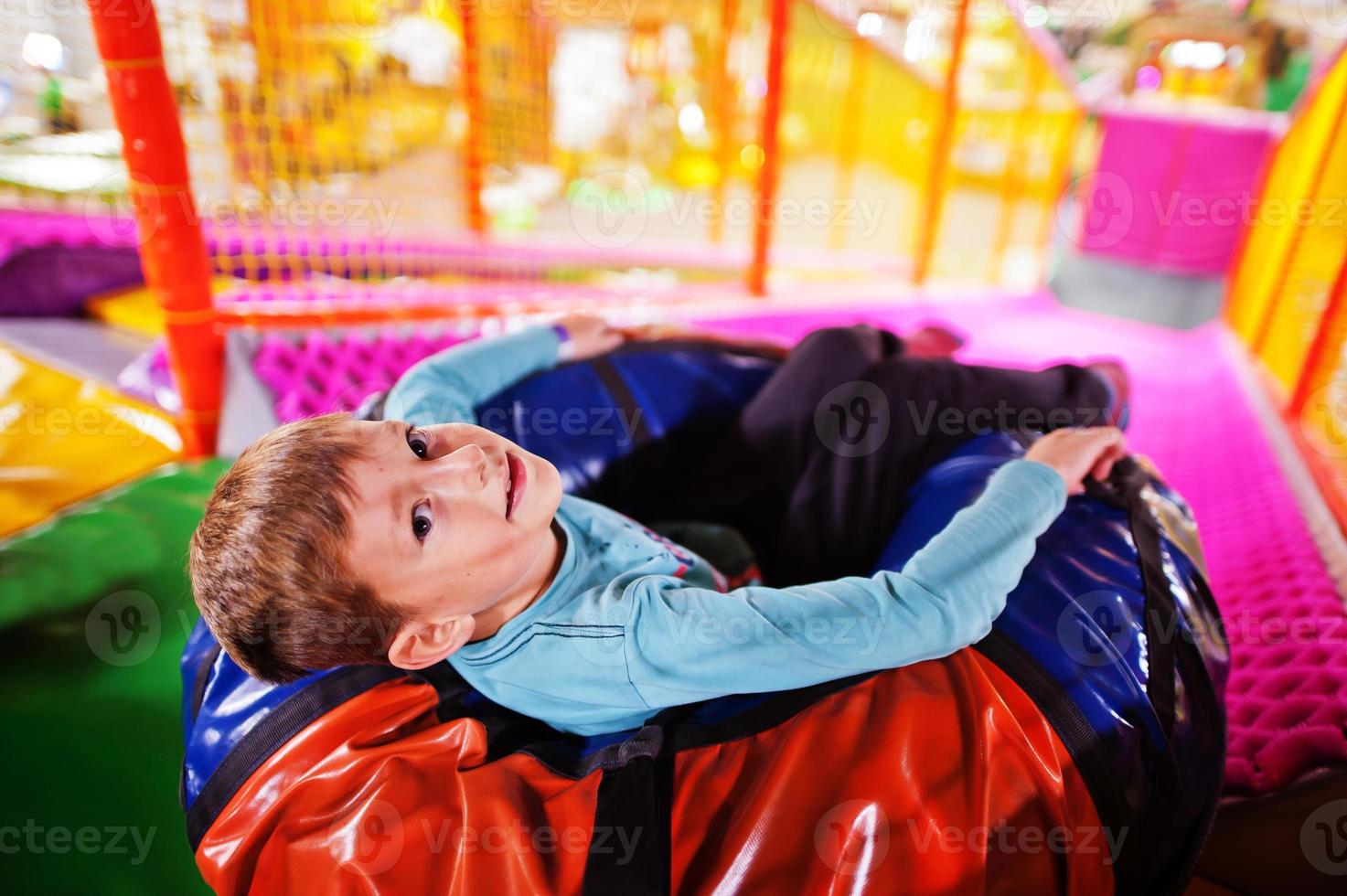 Happy boy sitting in tubing donuts enjoying slides in fun children center. photo