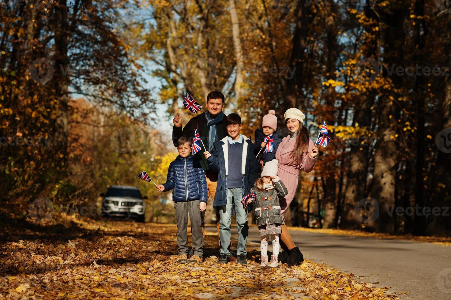 National holiday of United Kingdom. Large family with four kids holding british flags in autumn park.  Britishness celebrating UK. photo