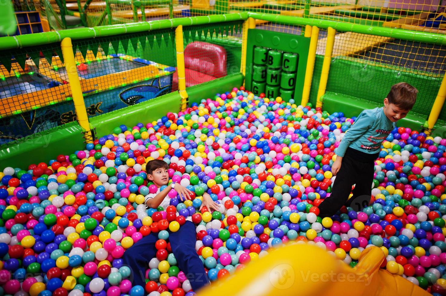Child playing in colorful ball pit. Day care indoor playground. Balls