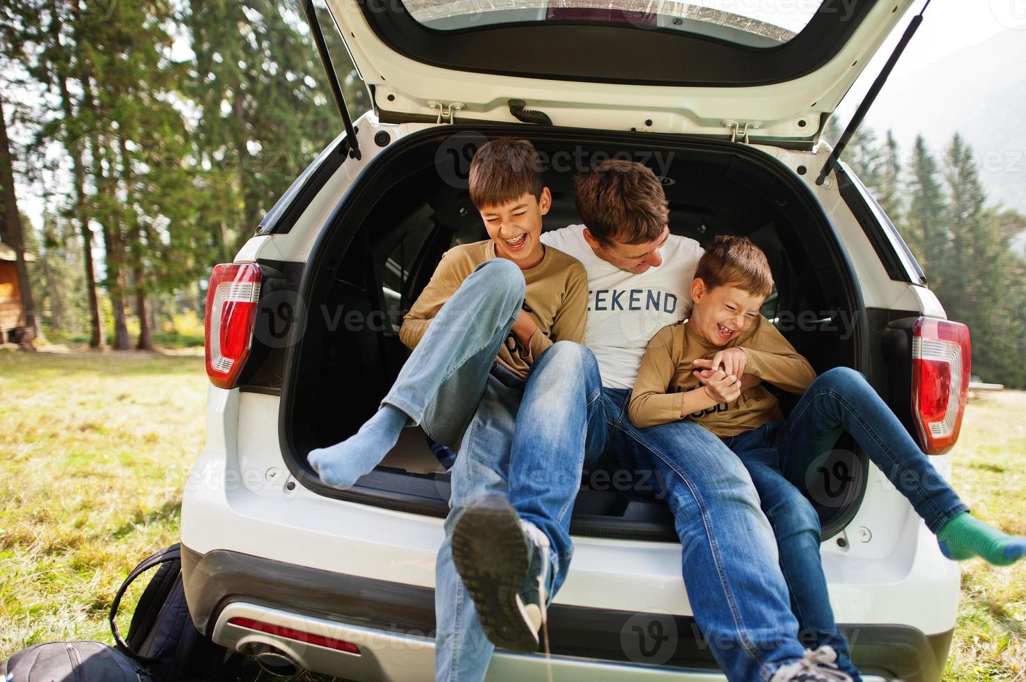 familia en el interior del vehículo. padre con sus hijos. niños en el baúl. viajar en coche por las montañas, concepto de ambiente. foto