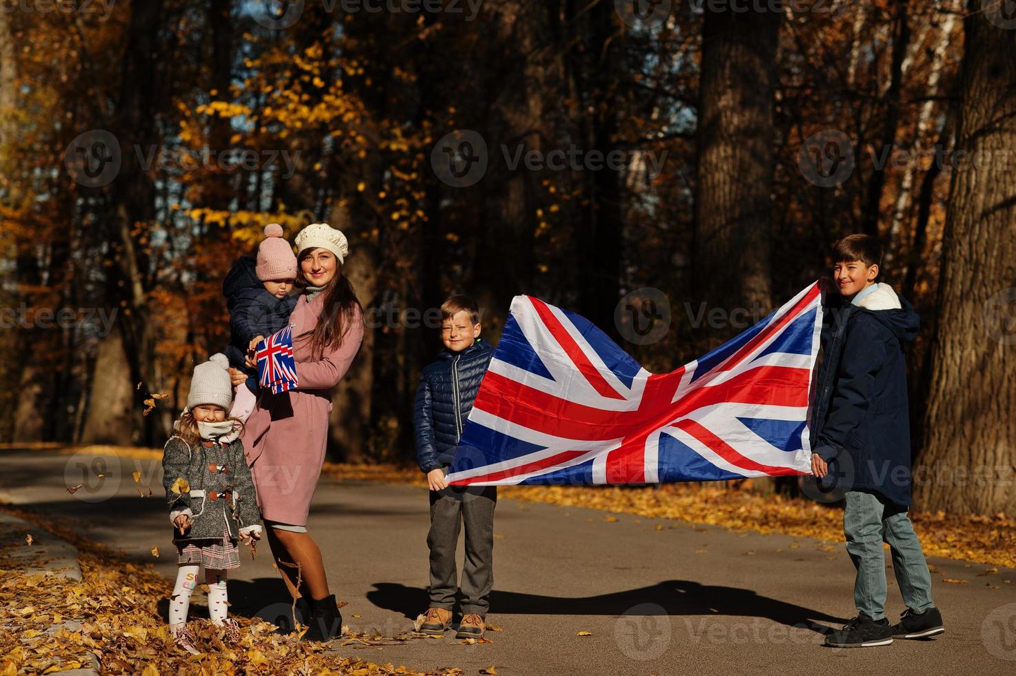 National holiday of United Kingdom. Family with british flags in autumn park.  Britishness celebrating UK. Mother with four kids. photo