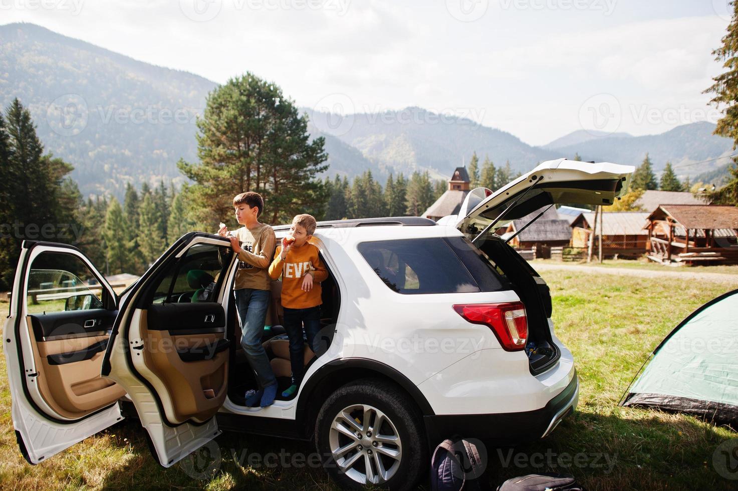 dos hermanos comen manzanas en el interior del vehículo. viajar en coche por las montañas, concepto de ambiente. foto