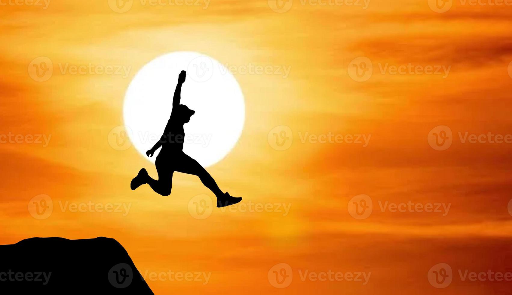 Silhouette of an athlete jumping on a rocky cliff photo