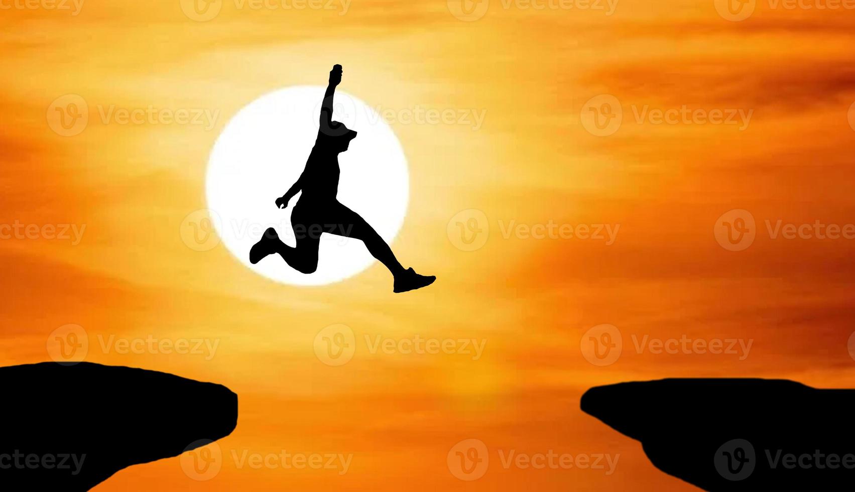 Silhouette of an athlete jumping on a rocky cliff photo