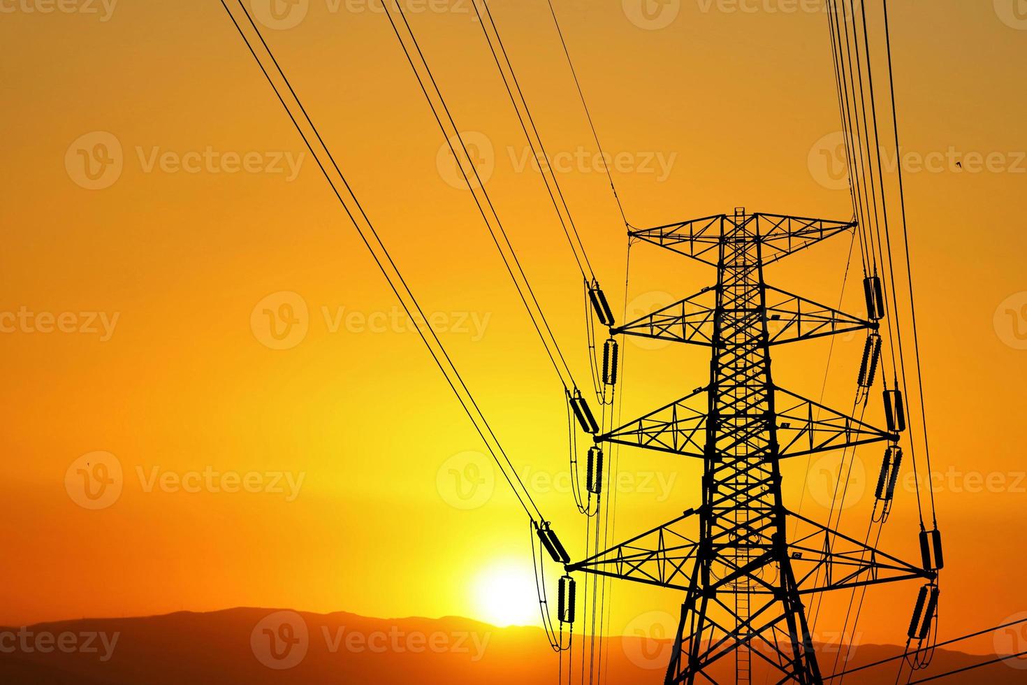 Silhouette of high voltage poles with electric wires. Silhouette of high voltage power line cables in an orange evening sunset. Steel structure of electric poles. electric power transmission concept photo
