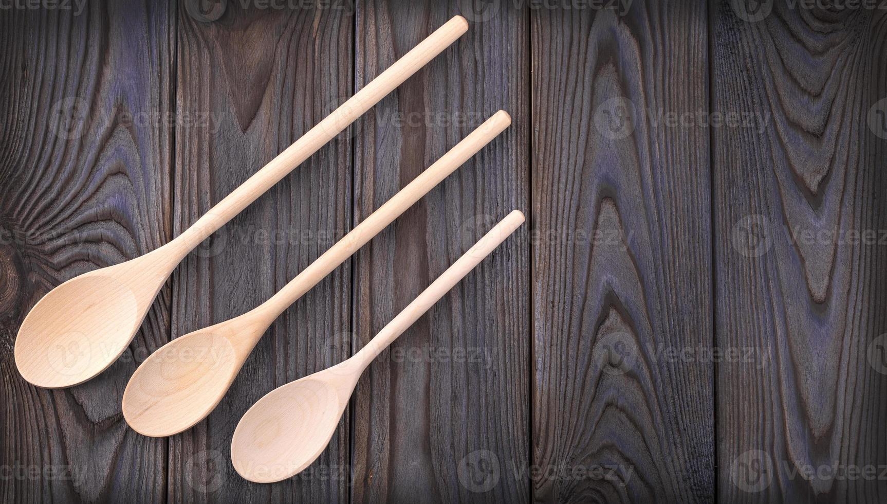 three wooden spoons on a dark wood table with copy space photo
